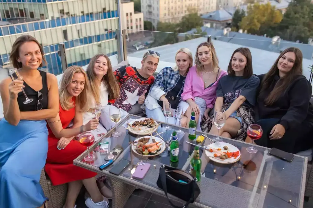 Компания друзей отдыхает на открытой террасе с едой и бокалами на вечеринке EventyOn